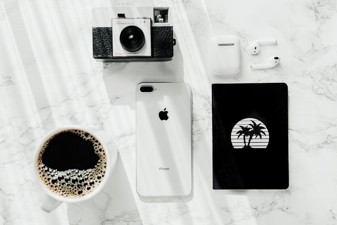Crafting Captivating Headlines: Your awesome post title goes here Stylish flat lay scene featuring a vintage camera, iPhone, AirPods, and coffee on a marble surface.